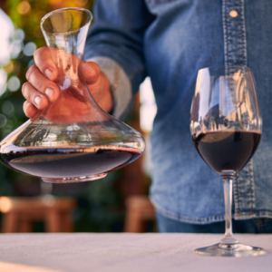 Man holding decanter of wine above table