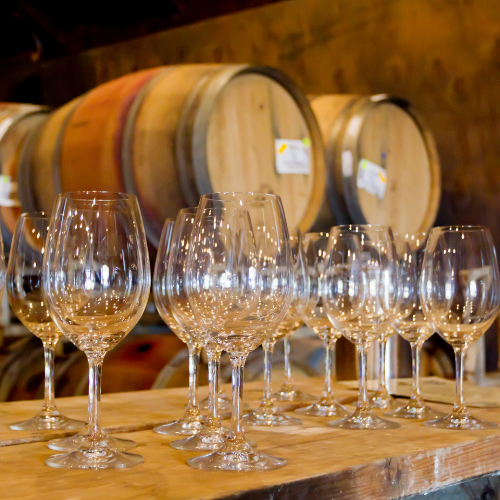 Photo of wine glasses in front of wine barrels