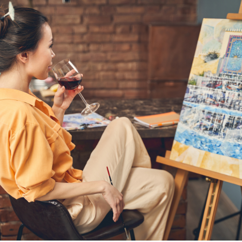Woman at easel with wine glass and paint brush