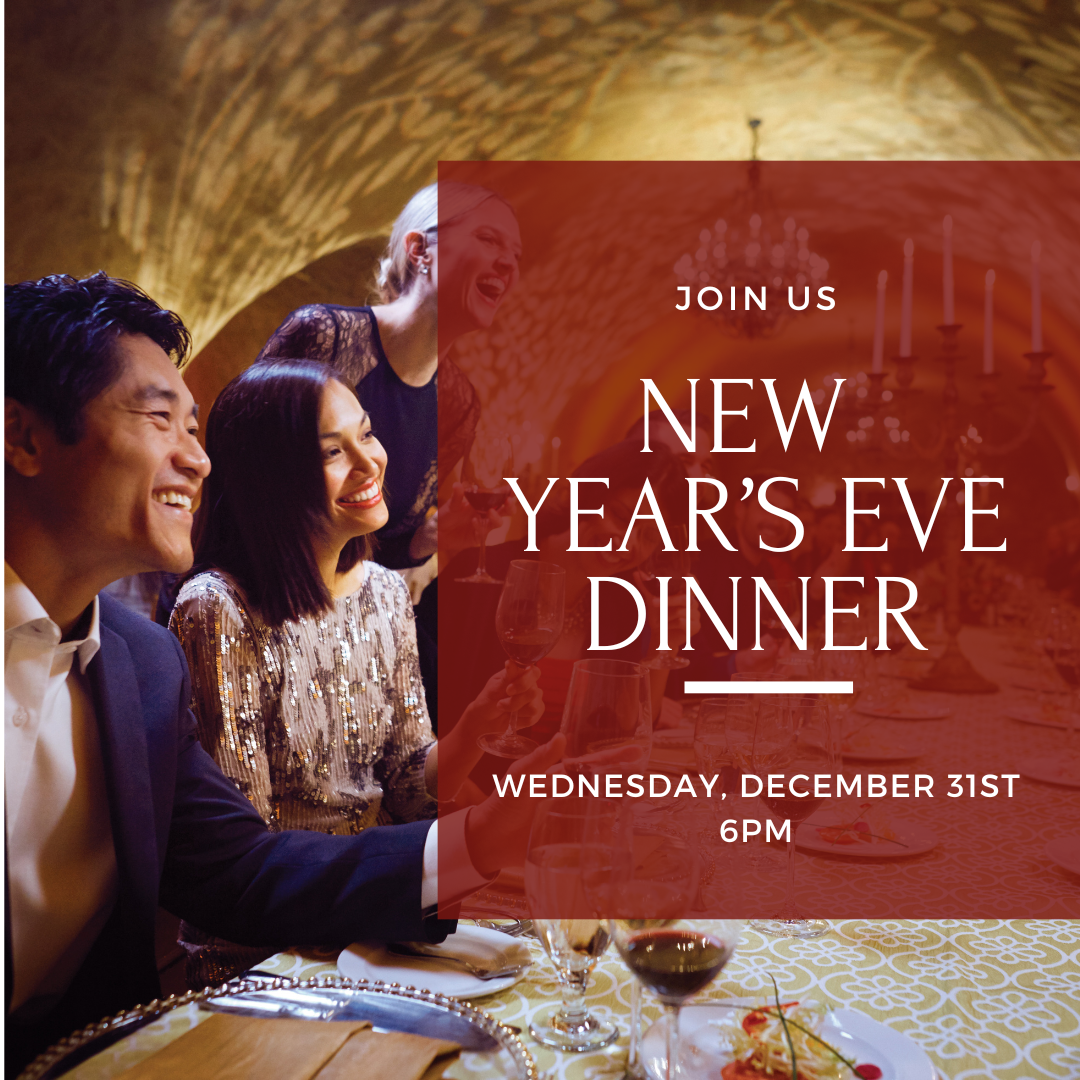 Guests enjoying an elegant New Year’s Eve dinner celebration in a candlelit wine cave at Trinitas Cellars