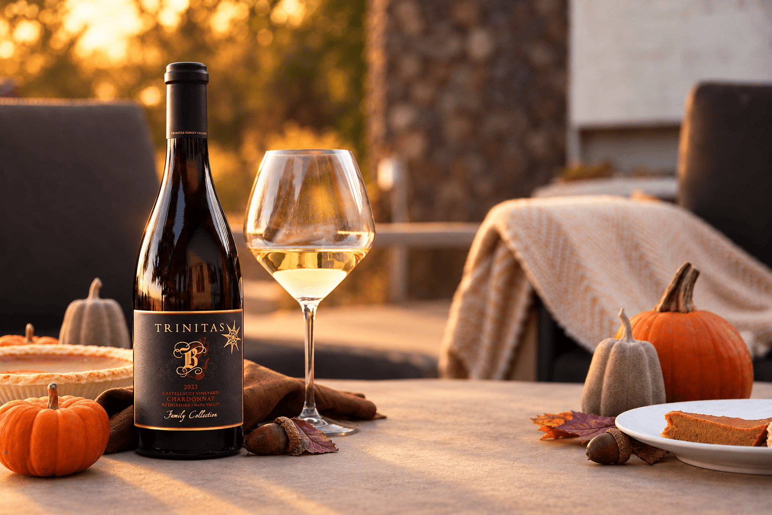 A bottle of Christian wine, glass, pumpkins, pie, and autumn decor on an outdoor table at sunset.