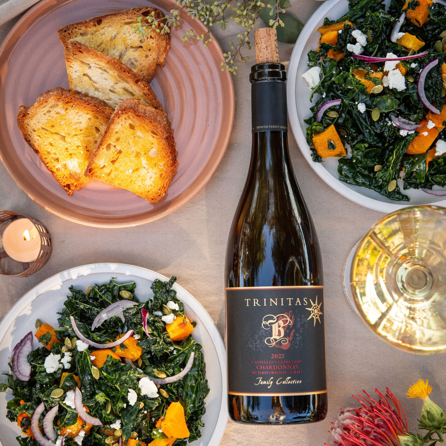 Fall table spread with Trinitas Chardonnay, kale and butternut squash salad, toasted bread, and autumn flowers.